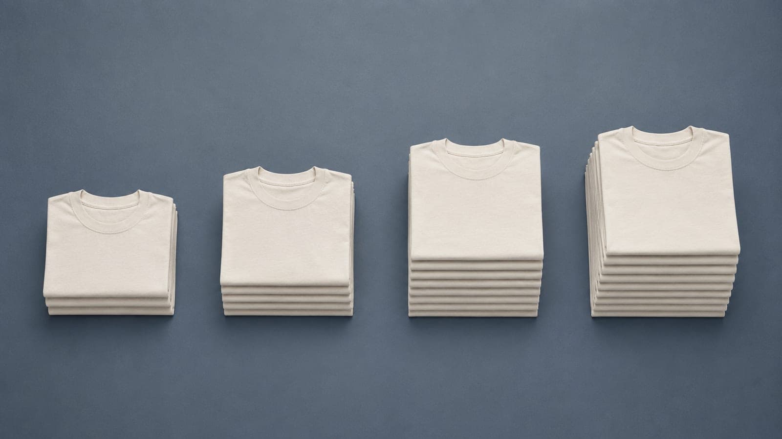 Four groups of folded t-shirts containing 3, 5, 10 and 12 pieces, arranged left to right