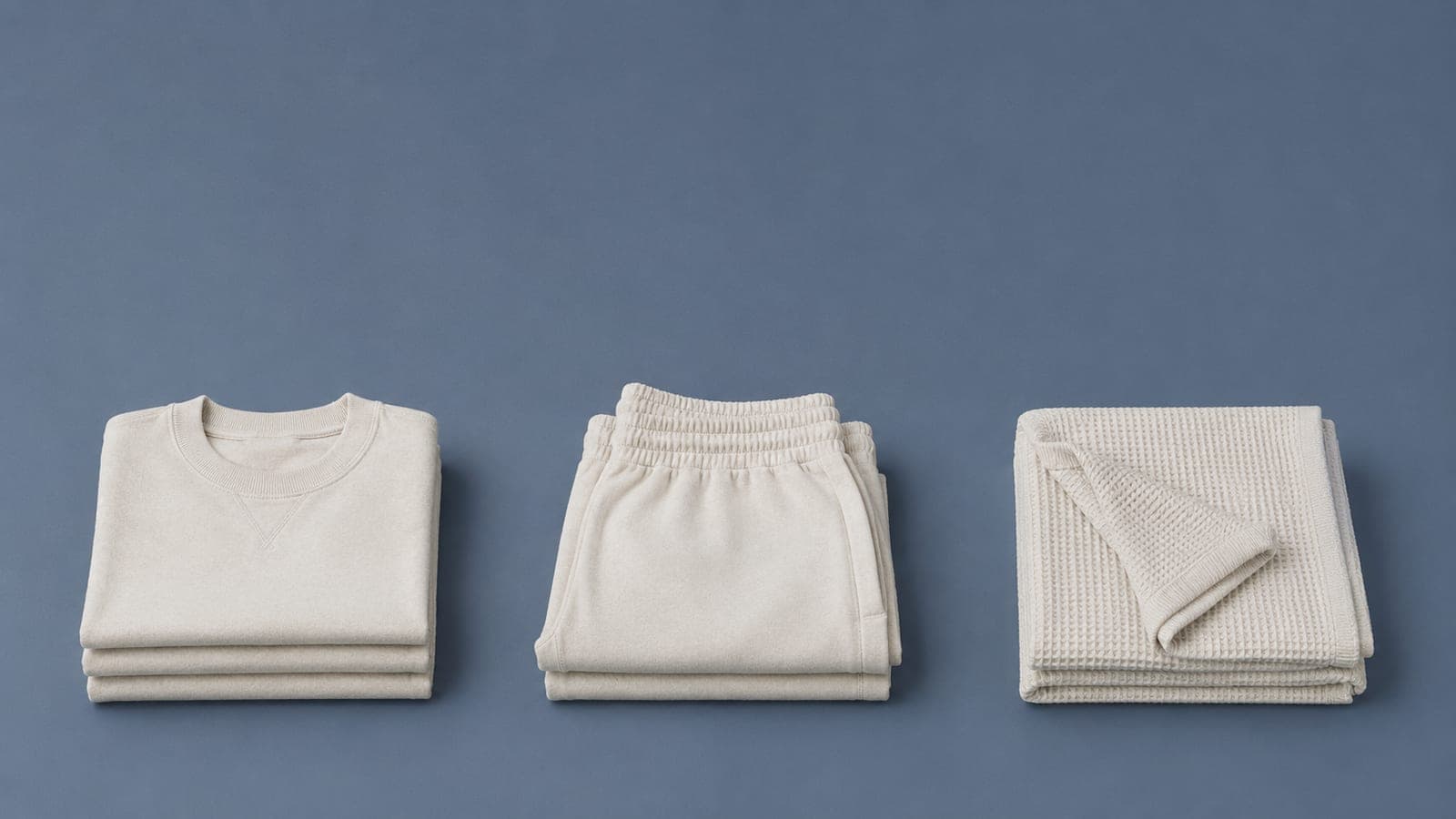 Three separate piles of folded cotton textiles arranged in distinct zones, illustrating sorting by material
